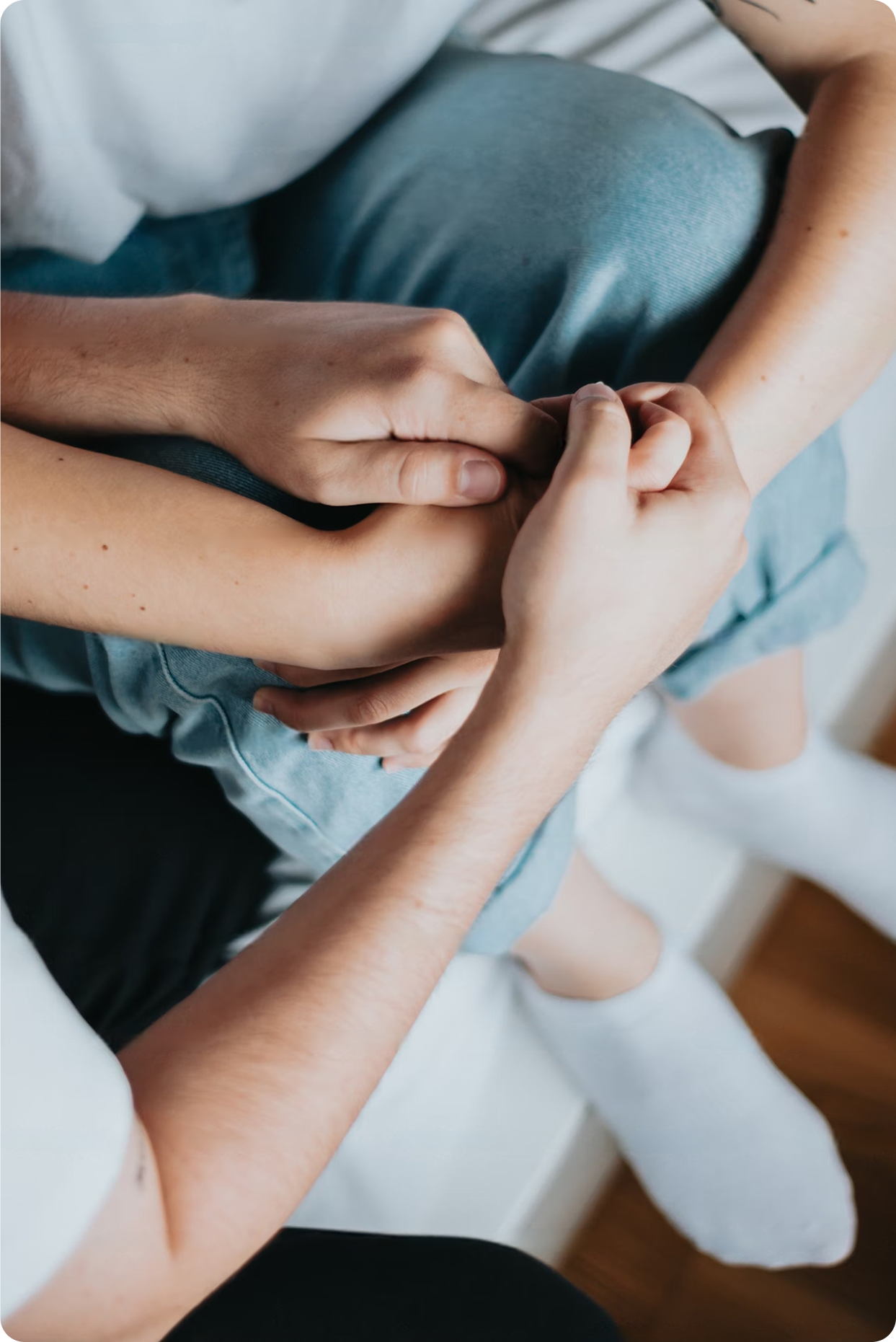 Two people sitting down holding hands in their laps.