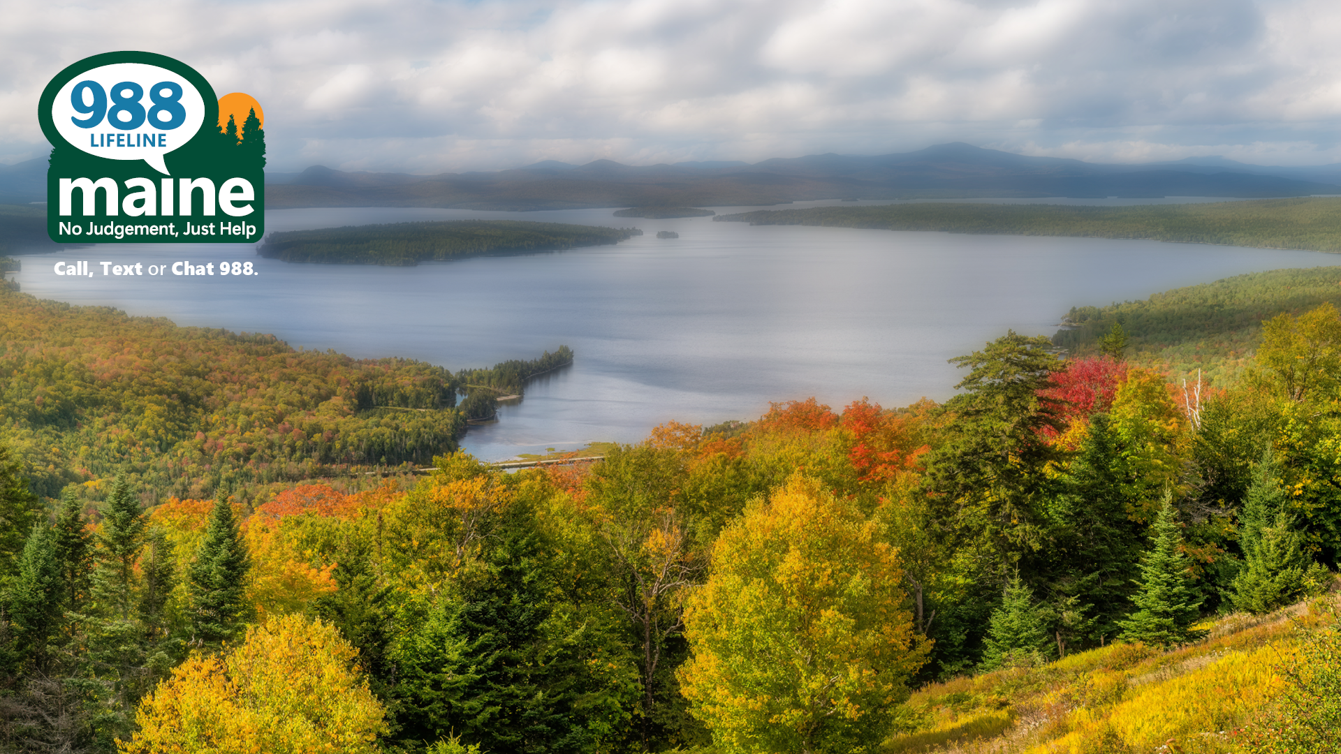 A sprawling view of autumn trees and rolling hills over a Maine lake